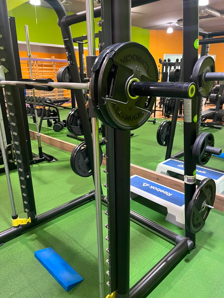 Dettaglio multipower Technogym con dischi 10 kg e 20 kg e spugna sul bilanciere
