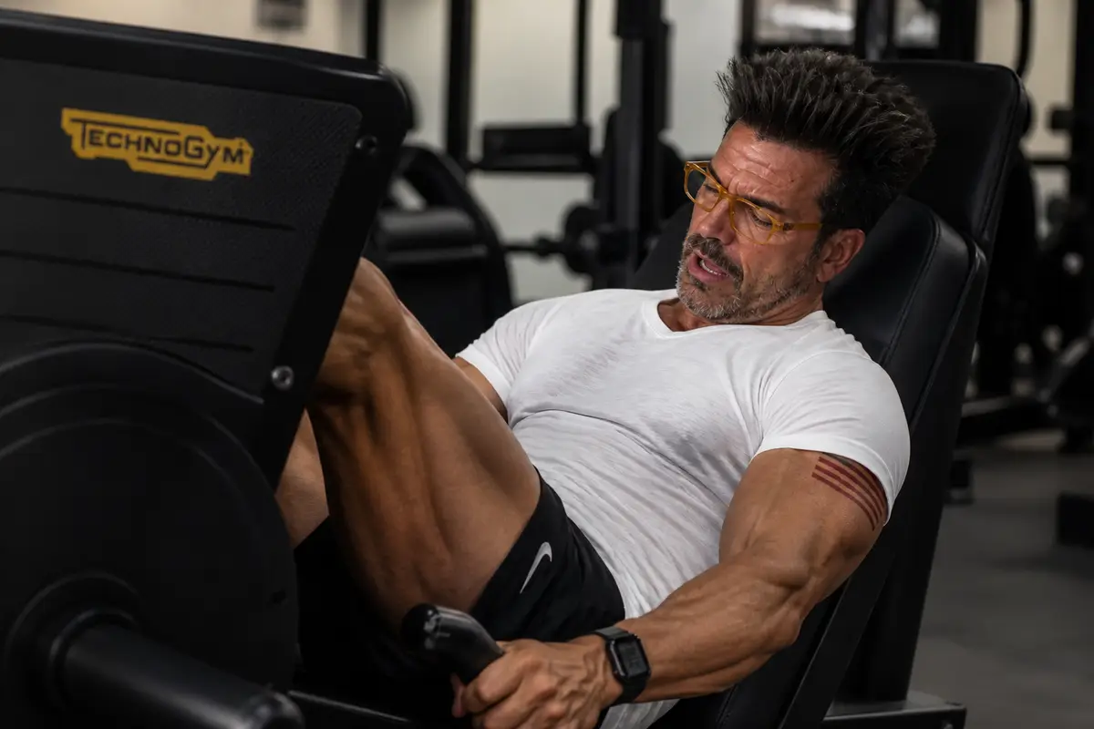 Gino Capon in pressa dopo leg day — gambe stanche, fotorealistico